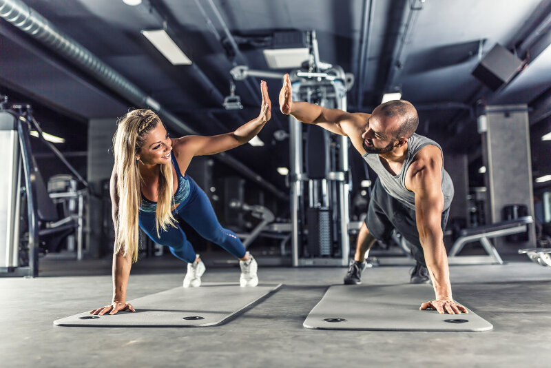 Sport couple doing plank exercise workout in fitness centrum. Man and woman practicing plank in the gym.