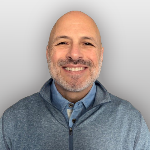 Paul Scardina, smiling man in a denim button up with gray pullover
